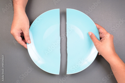 Hands of a man and a woman breaking the dish and split it as two halves, fracture problem in relationships that hard to conciliate