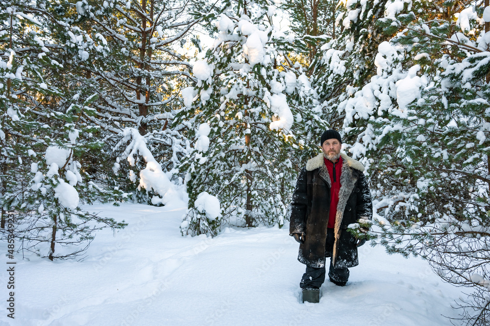 Portrait of serious brutal man with beard and in warm sheepskin coat in middle of snowy forest. Life away from civilization. Copy space Portrait of serious brutal man with beard and in warm sheepskin coat in middle of snowy forest. Life away from civilization. Copy space