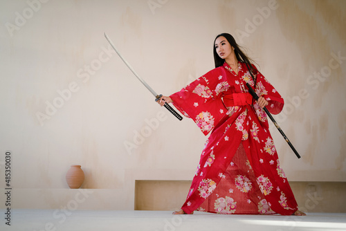 A young girl in the red kimono with the katana sword. The woman warrior concept. photo