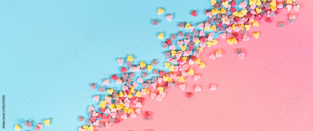 Fototapeta premium flatlay mockup made of multi-colored sugar hearts on a turquoise background in the form diagonally divides the sheet in half