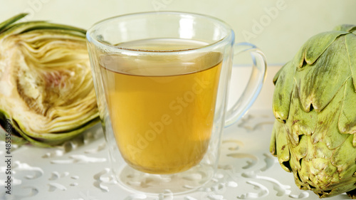 Artichoke tea glass cup. Raw artichoke vegetables with herbal beverage.