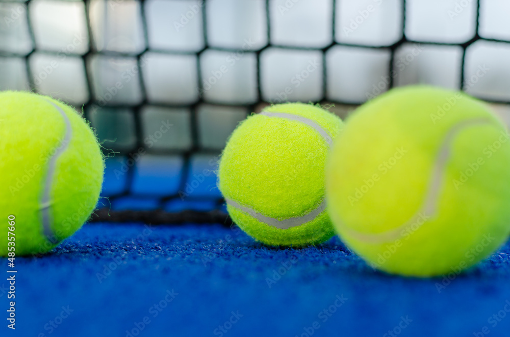 Selective focus. Three balls on a blue paddle tennis court.