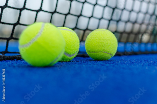 Selective focus. Three balls on a blue paddle tennis court. © VicVaz