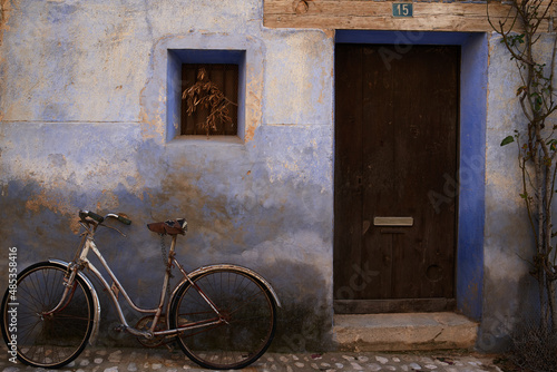 Home entrance with number fifteen and blue wall with old bicycle, fragment of a typical house in an antique town in Teruel, Spain.