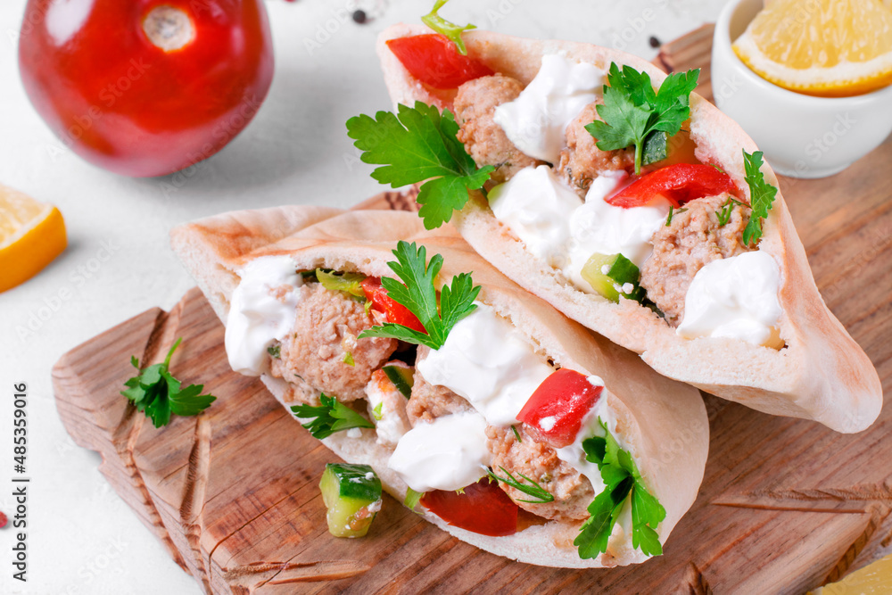 Pita pocket stuffed with meatballs and vegetables topped with sour cream and cilantro. Arabian, Turkish and Greek cuisines meal