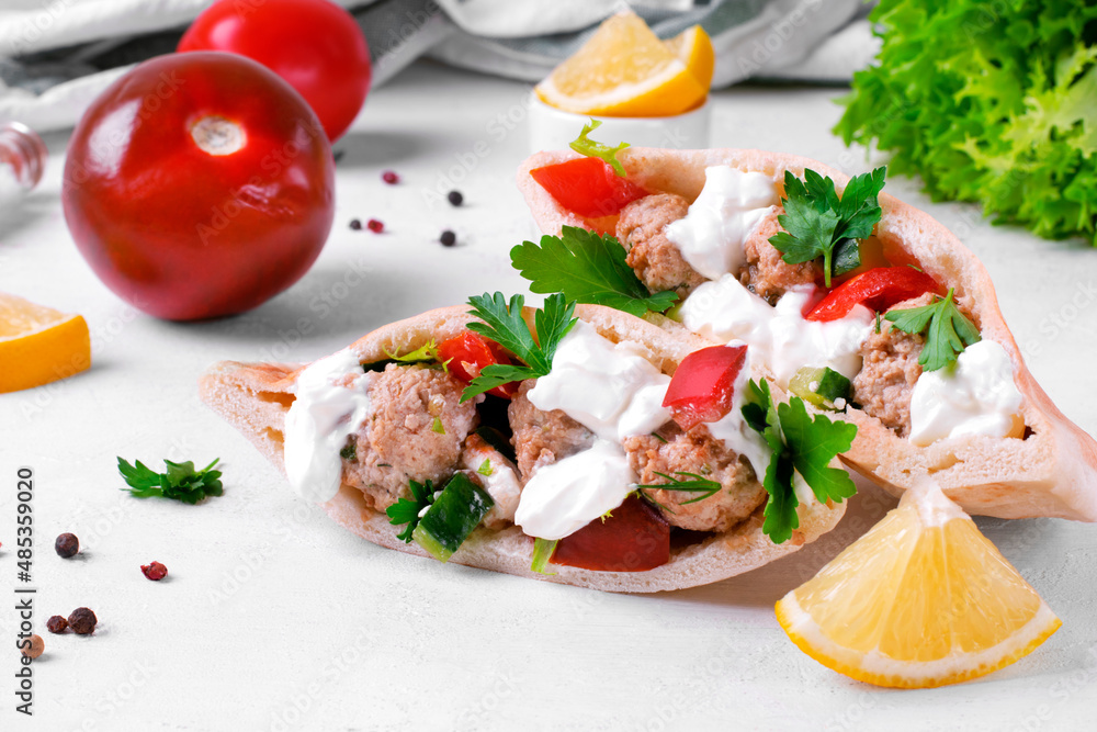 Pita pocket stuffed with meatballs and vegetables topped with sour cream and cilantro. Arabian, Turkish and Greek cuisines meal