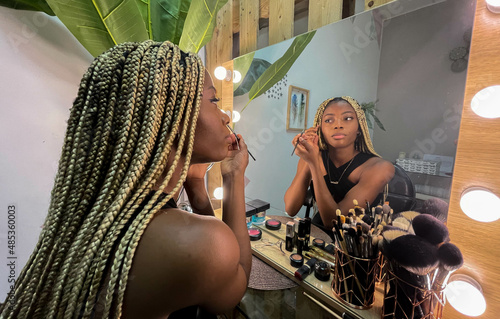 Afro young woman putting on makeup