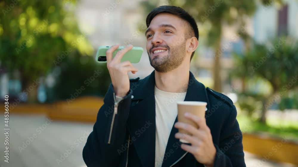 Young hispanic man talking on the smartphone drinking coffee at park Young hispanic man talking on the smartphone drinking coffee at park