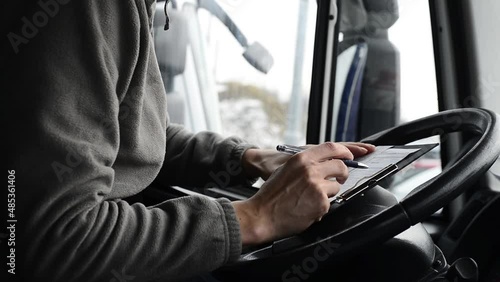 Truck driver doing his paperwork. Driver finishes his day shift in a cab.
