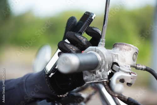 Motorcyclist hand with a mobile phone close up.