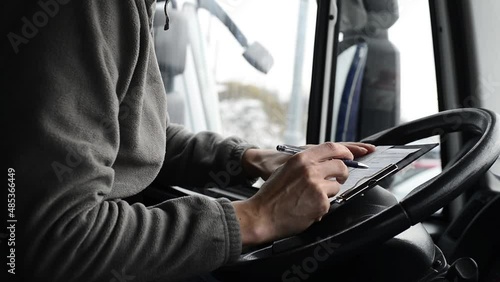 Truck driver doing his paperwork. Driver finishes his day shift in a cab.