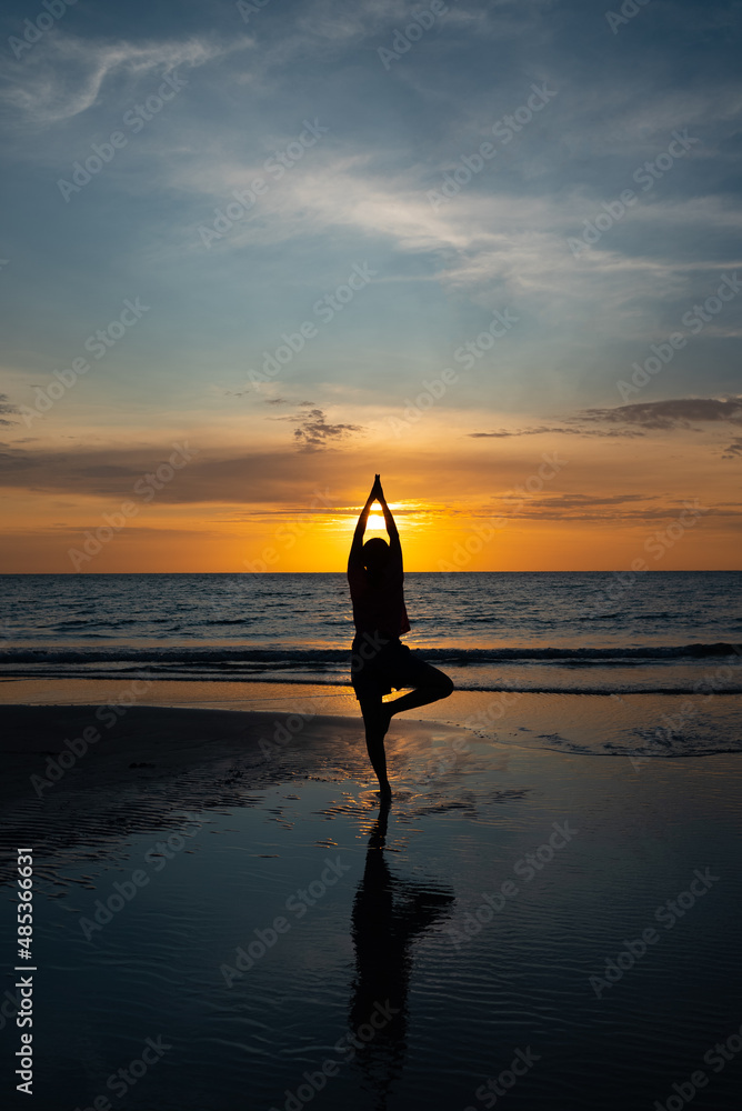 Silhouette of woman Meditate on Beach at Sunset