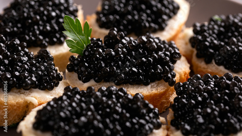 Slices of bread with black caviar on plate