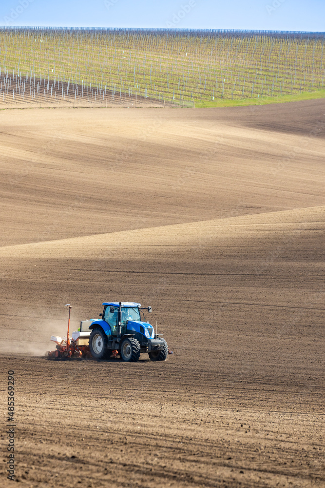 Fototapeta premium Tractor with seed drill in early spring landscape