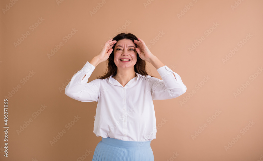 a happy brunette woman in a white shirt stands on a beige background with a place for text a happy brunette woman in a white shirt stands on a beige background with a place for text
