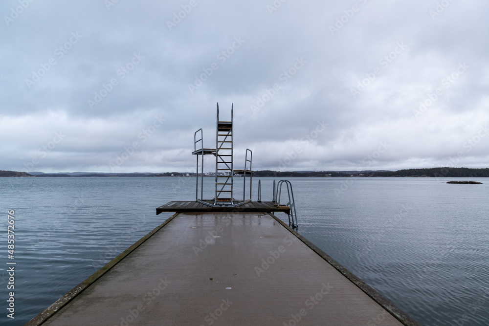 Bridge and diving tower surrounded by calm water on grey day
