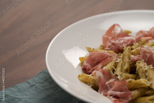 Penne pasta with capocollo, pesto and parmesan cheese