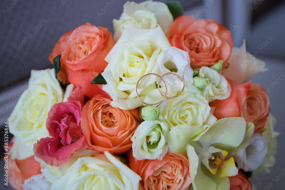 Wedding rings lie on a bouquet of roses of different colors Wedding rings lie on a bouquet of roses of different colors