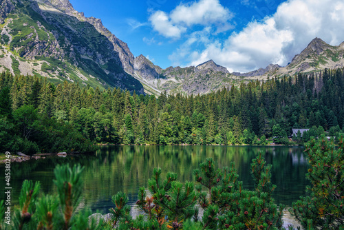 Beautiful summer landscape of High Tatras, Slovakia - Poprad lake, lush forest, mountains and white clouds on the sky