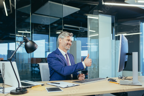 Senior and experienced employee, advises the buyer on a video call, the man works in a modern office uses webcam © Liubomir