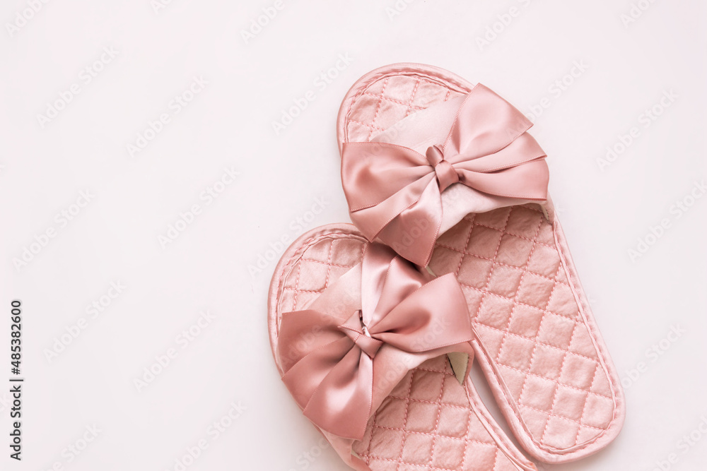 Close-up of pink satin female glamorous home slippers with bows isolated on a white background. Top view Close-up of pink satin female glamorous home slippers with bows isolated on a white background. Top view