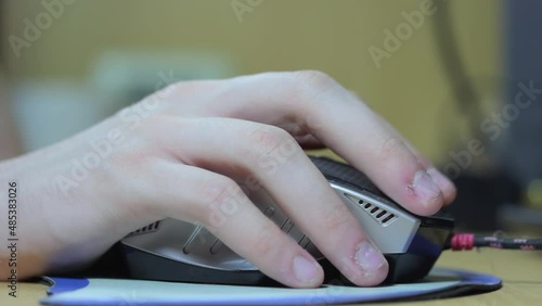 A hand with a computer mouse. He moves it and presses the button with his finger.