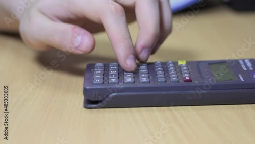 The calculator is on the table. A man's hand uses it for calculations.