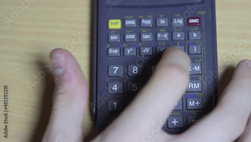 The man uses a calculator for calculations. He presses the buttons with his hand.