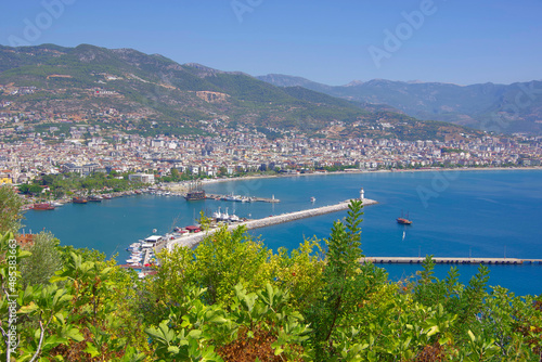 Turkey. Alanya 09.14.21. View from a height of the city among the mountains to the ships in the sea and in the port on the pier.