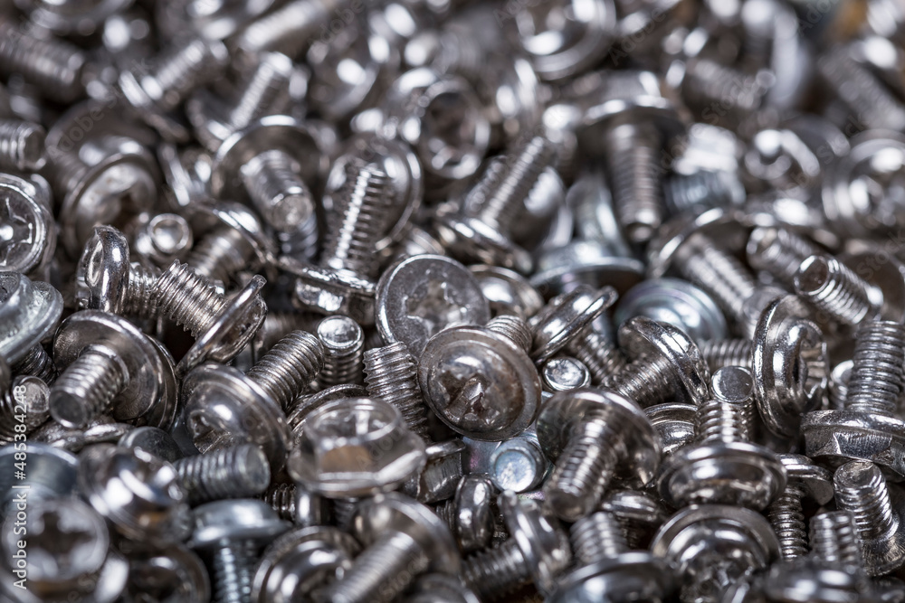 Close up of chrome machine screws on the counter of a hardware store. Background of the screws. Close up of chrome machine screws on the counter of a hardware store. Background of the screws.