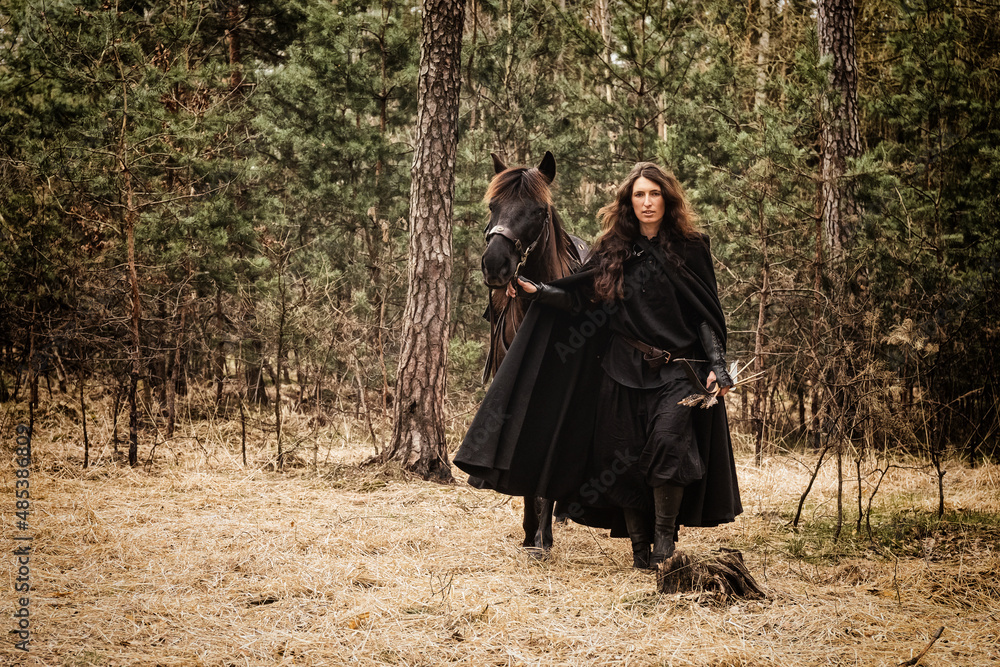 beautiful woman with long hair leading his horse by the bridle, coming out into the clearing from the forest