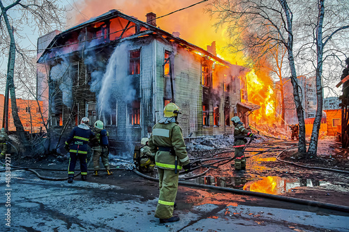 Firefighters extinguish a fire in a two-story wooden house
