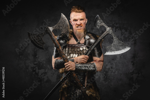 Fototapeta Violent viking with dual axes against dark background