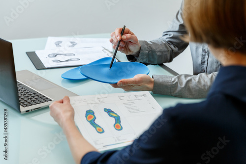 Doctor consulting patient on custom orthotic insoles in a clinic for a personalised custom fit. photo