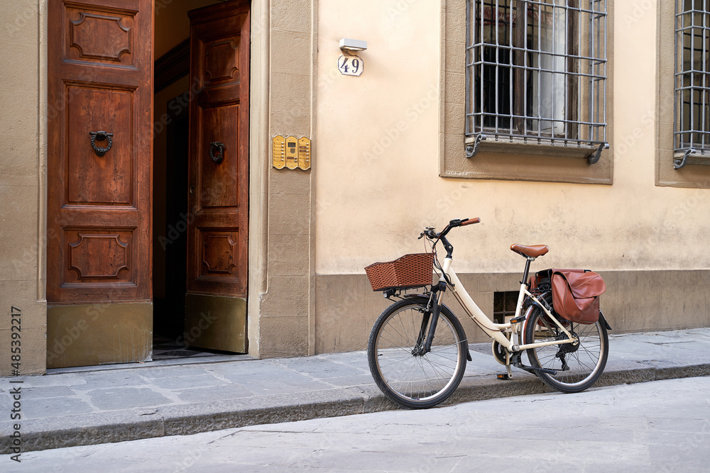Bicycle with basket and brown leather bag or pannier parked on the old street in Italy