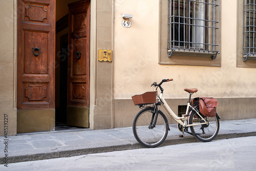 Bicycle with basket and brown leather bag or pannier parked on the old street in Italy