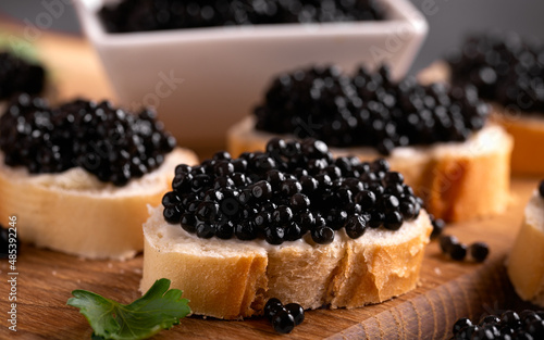 Slices of bread with black caviar on rustic dark background