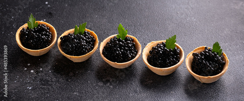 Tartlets with black caviar on rustic background