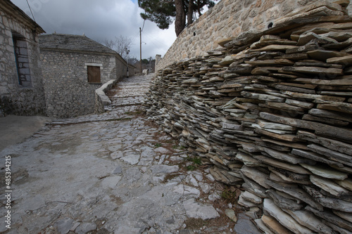 Scale style roof tiles stacked next to a stone path at the traditional village of Kalarites in Tzoumerka, Greece photo