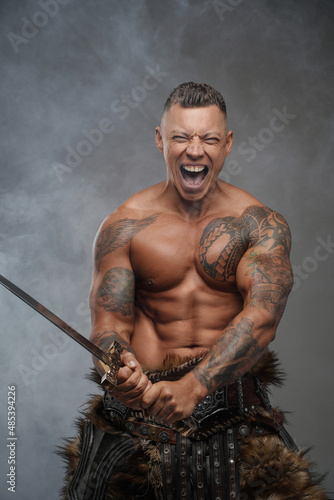Furious warrior with sword against background with smoke