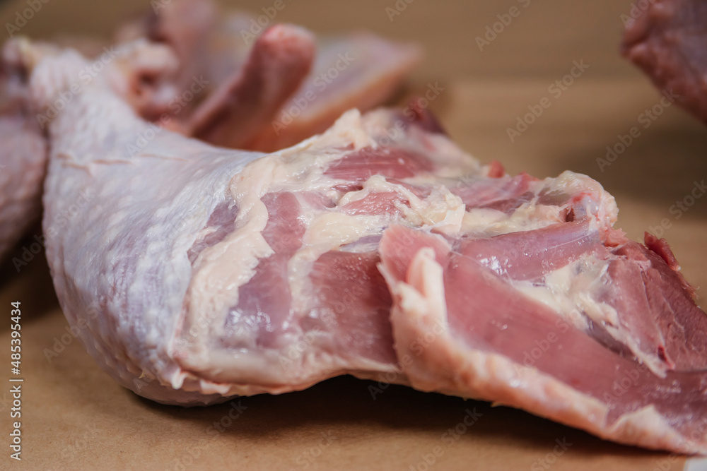 Male hands cut the carcass of a large Turkey on a wooden board. Fresh meat.