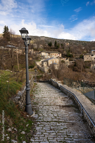 Old lamp post on a stone path leading to the traditional village of Kalarites in Tzoumerka, Greece photo