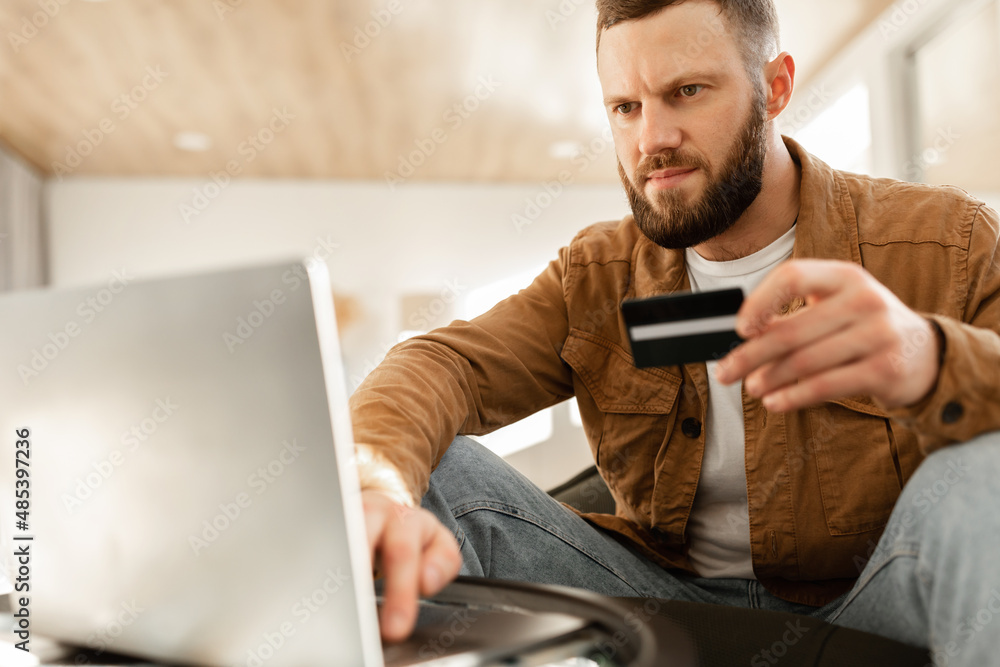 Man Using Laptop And Credit Card Shopping Online Sitting Indoors Man Using Laptop And Credit Card Shopping Online Sitting Indoors