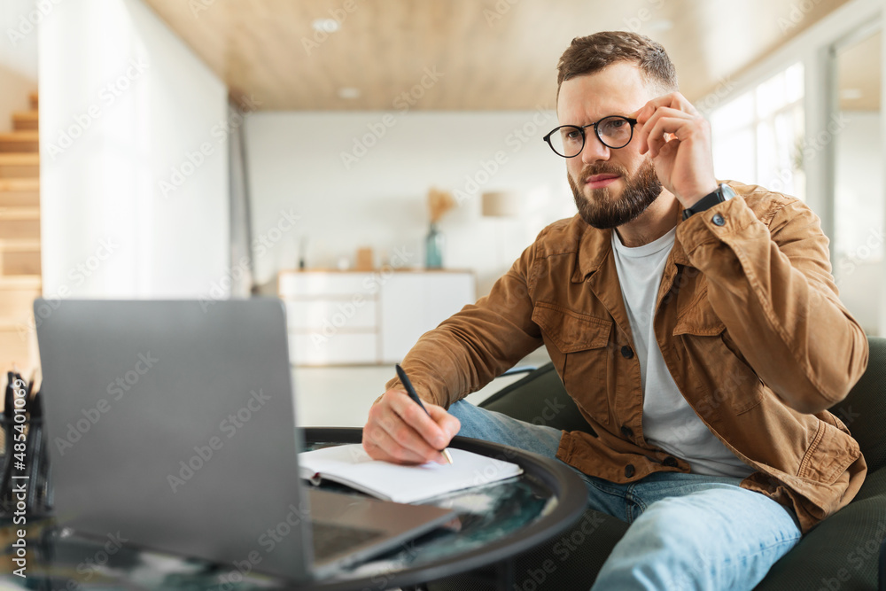 Businessman Looking At Laptop Touching Eyeglasses Taking Notes At Home Businessman Looking At Laptop Touching Eyeglasses Taking Notes At Home