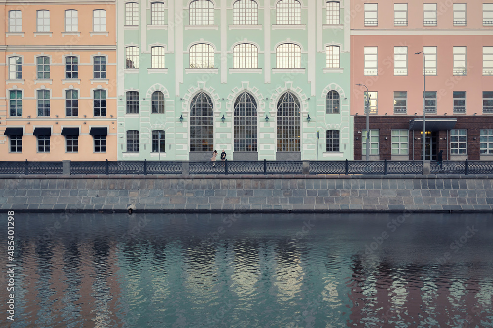 A river in front of an embankment against a colorful facade by autumn day