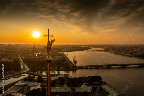 The golden angel on the cross of the Peter and Paul Fortress at sunrise, reflection of the orange sky on the water, drawbridges Troitsky and Liteiny  photo