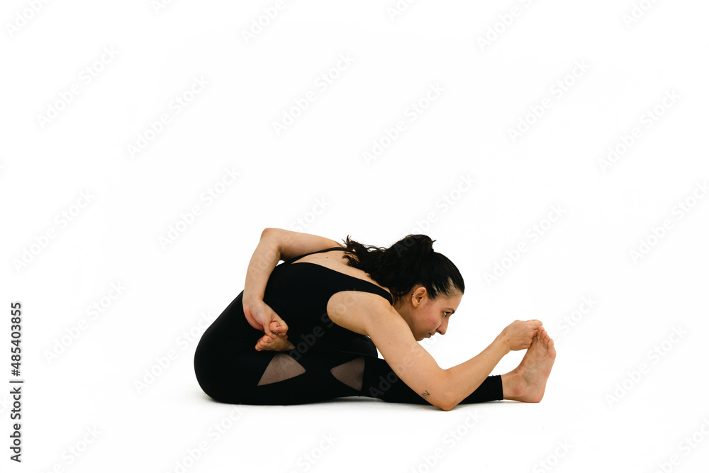 Woman doing yoga asana in white background. Black outfit. Ashtanga, Vinyasa, Hatha
