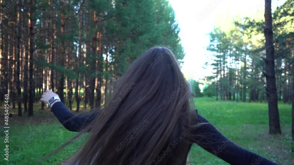 A young woman happily walks in the park. Jumping happily, moving his arms. A young woman happily walks in the park. Jumping happily, moving his arms.