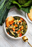 Tuscan bread soup made with toasted bread and vegetables. Ribollita. Cannellini beans, lacinato kale, cabbage verza, carrot, celery, potatoes, and onion. Itralian food. Vertical image. Directly above.