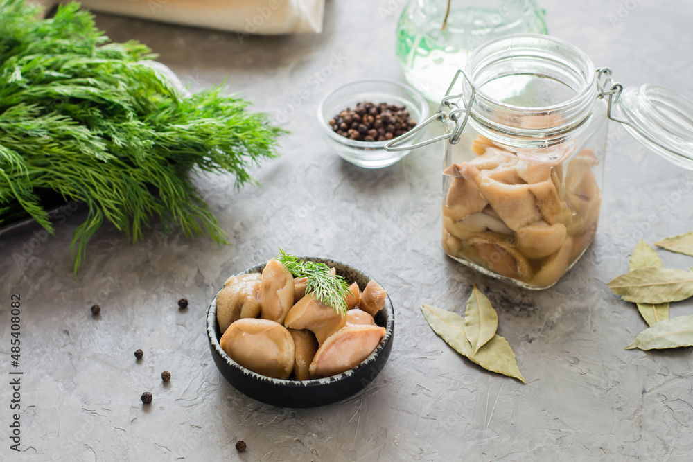 Delicious pickled mushrooms in a bowl and in a glass jar on the table. Vegetarian organic food.